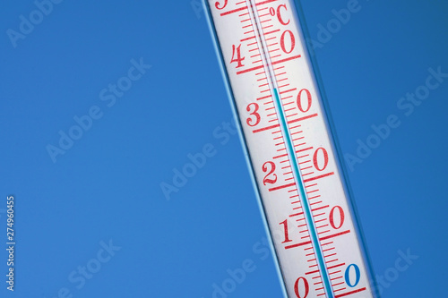 Thermometer during hot weather with sky in background