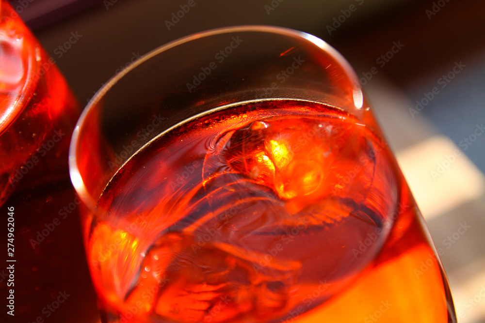 close up of red cocktail with ice cubes in wine glass
