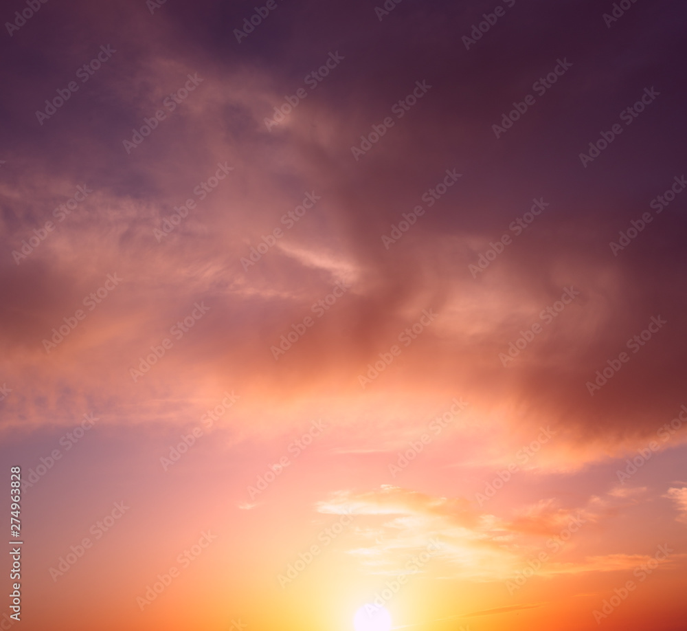 The bright orange sun rises against the backdrop of purple clouds.
