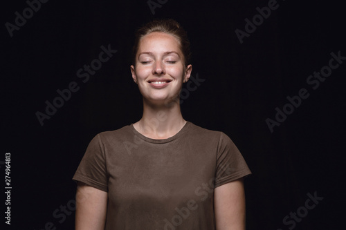 Close up portrait of young woman isolated on black studio background. Photoshot of real emotions of female model with closed eyes. Thinking and smiling. Facial expression, human emotions concept.