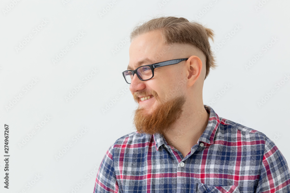 Positive emotions and people concept - young bearded man in glasses is smiling on white background