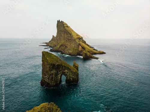 Aerial view of Drangarnir cliff and Tindholmur islands from above taken during early morning hike in spring with dark blue water and lush greens (Faroe Islands, Denmark, Europe) photo