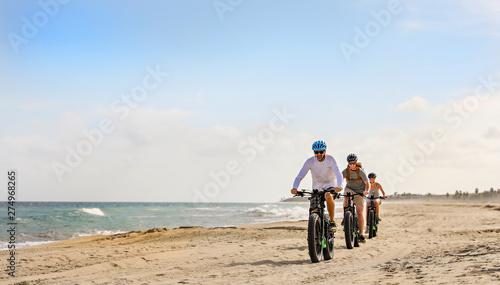 Family rides their e bikes on the beach in the Baja. 