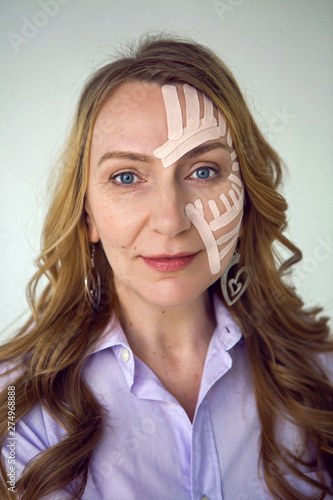 woman in the purple shirt kinesiotaping on the face photo