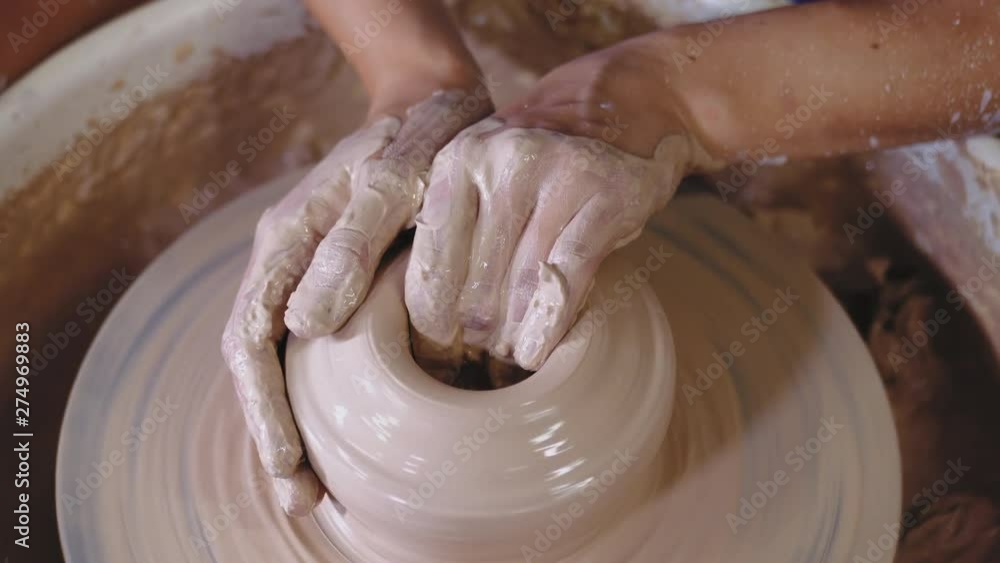 Man works his hands with clay. Process of creating product from clay on potter's wheel. Side view of artisan making pot or jug. Small business owner in workshop. Man works his hands with clay. Process of creating product from clay on potter's wheel. Side view of artisan making pot or jug. Small business owner in workshop.