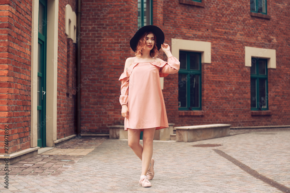 Girl in a beautiful pink dress and black hat. The girl travels. Girl on tour in Europe. Girl walking through the beautiful streets