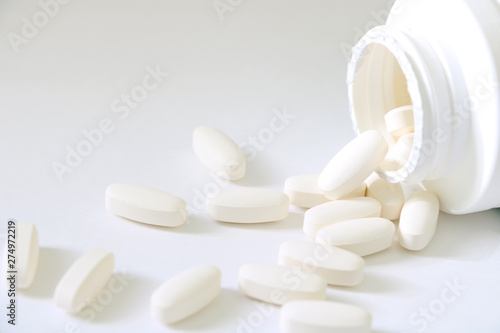 Medicine pills and a bottle of medicine isolated on a bright background