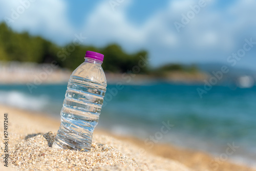 Bottle of fresh cold water on beach sand