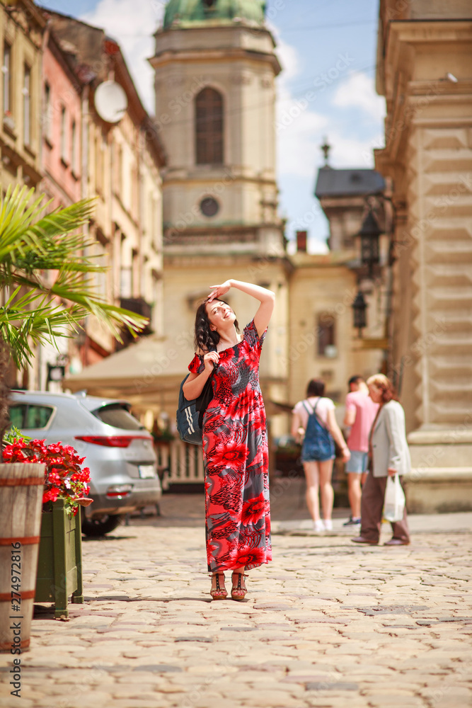 Pensive woman in long colorful dress on street of tourist old European city
