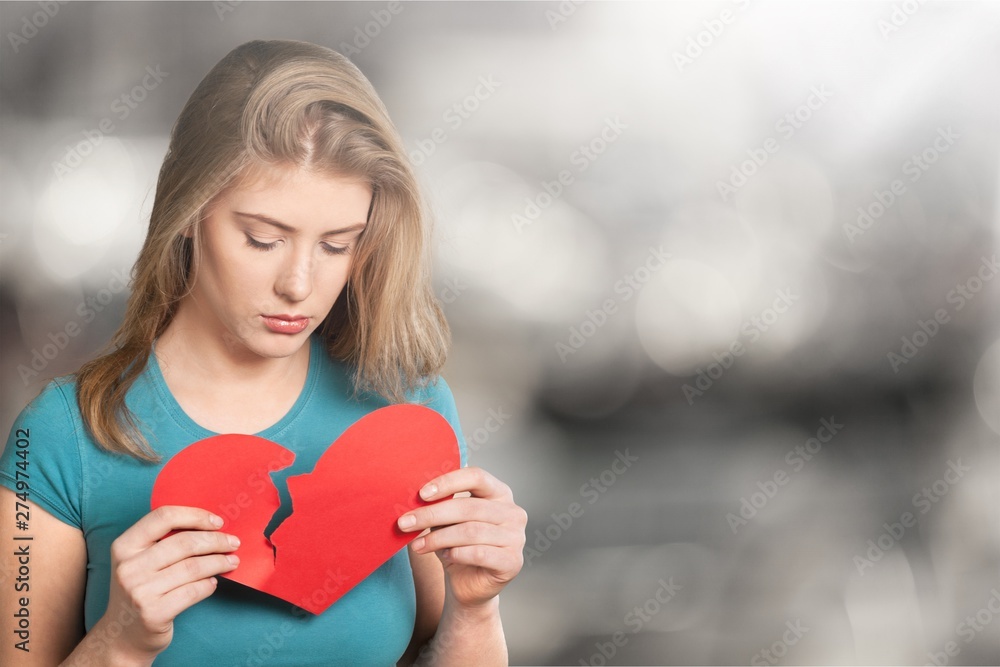 Young woman is holding a broken heart isolated on background. Young woman is holding a broken heart isolated on background.