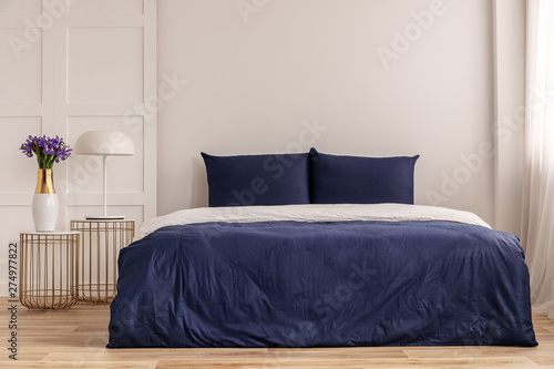 Vászonkép Simple navy blue and white bedroom interior with cozy bed with pillows and duvet