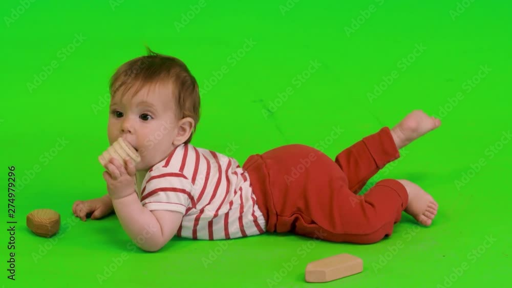 Cute baby girl plays happily with wooden toys over a green screen. Cute baby girl plays happily with wooden toys over a green screen.