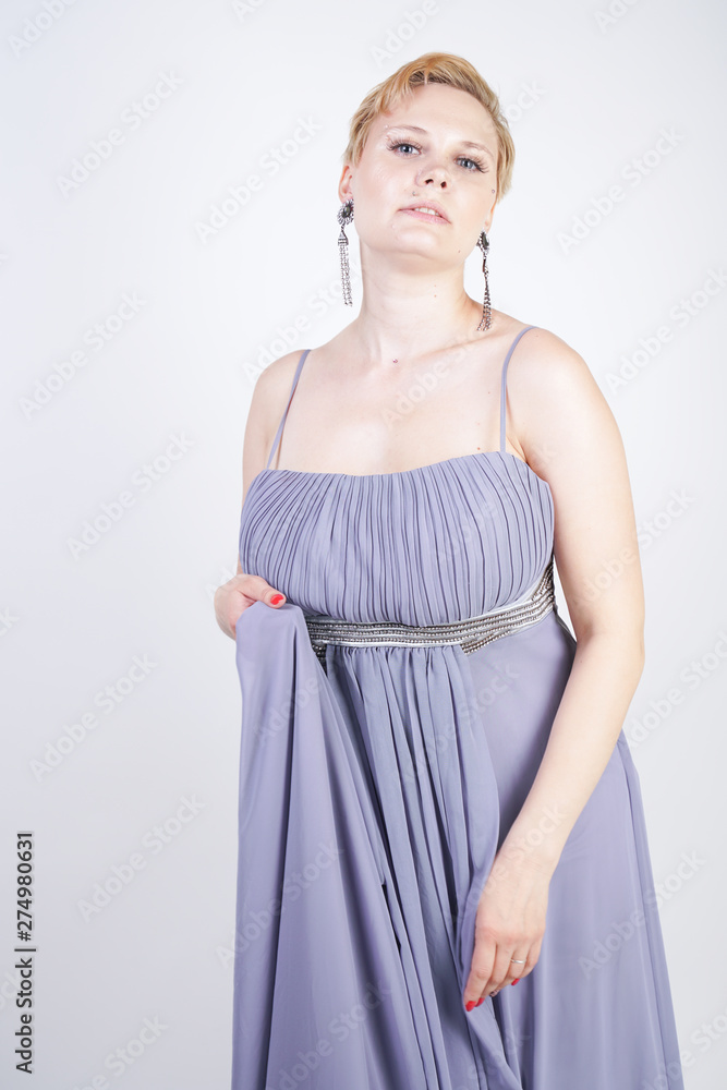 elegant thick female in a grey long dress. pretty plus size woman in evening dress standing on white studio background. short hair chubby girl in gray clothes posing alone. elegant thick female in a grey long dress. pretty plus size woman in evening dress standing on white studio background. short hair chubby girl in gray clothes posing alone.