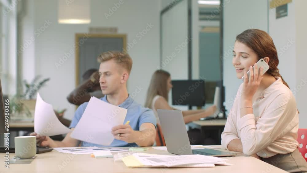 Young woman flirting on mobile phone at coworking space. Smiling lady Young woman flirting on mobile phone at coworking space. Smiling lady