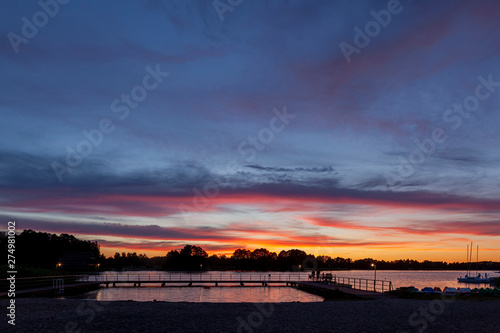 Fototapeta Naklejka Na Ścianę i Meble -  Piękny zachód słońca nad jeziorem Kalwa na Mazurach w Polsce., na pierwszym planie pomost na jeziorze.
