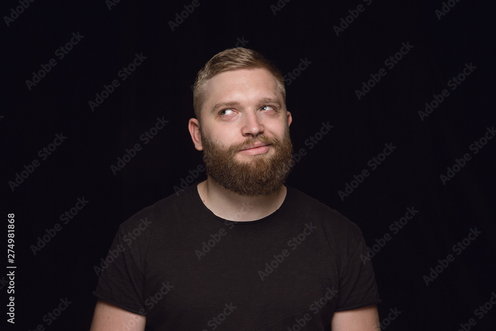 Close up portrait of young man isolated on black studio background. Photoshot of real emotions of male model. Dreaming and smiling, hopeful and happy. Facial expression, human emotions concept. Close up portrait of young man isolated on black studio background. Photoshot of real emotions of male model. Dreaming and smiling, hopeful and happy. Facial expression, human emotions concept.