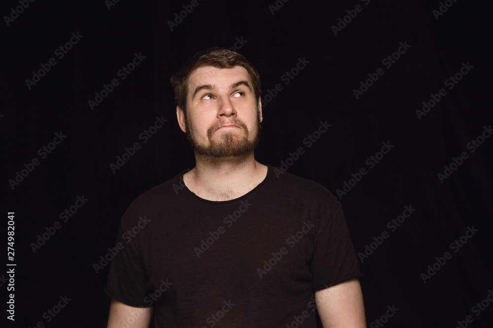 Close up portrait of young man isolated on black studio background. Photoshot of real emotions of male model. Dreaming and smiling, hopeful and happy. Facial expression, human emotions concept. Close up portrait of young man isolated on black studio background. Photoshot of real emotions of male model. Dreaming and smiling, hopeful and happy. Facial expression, human emotions concept.