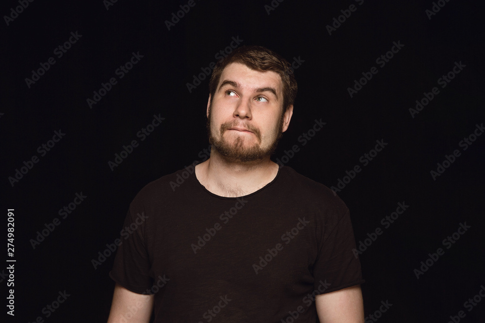 Close up portrait of young man isolated on black studio background. Photoshot of real emotions of male model. Dreaming and smiling, hopeful and happy. Facial expression, human emotions concept. Close up portrait of young man isolated on black studio background. Photoshot of real emotions of male model. Dreaming and smiling, hopeful and happy. Facial expression, human emotions concept.