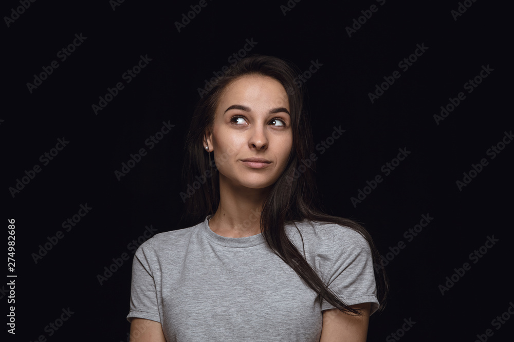 Close up portrait of young woman isolated on black studio background. Photoshot of real emotions of female model. Dreaming and smiling, hopeful and happy. Facial expression, human emotions concept. Close up portrait of young woman isolated on black studio background. Photoshot of real emotions of female model. Dreaming and smiling, hopeful and happy. Facial expression, human emotions concept.