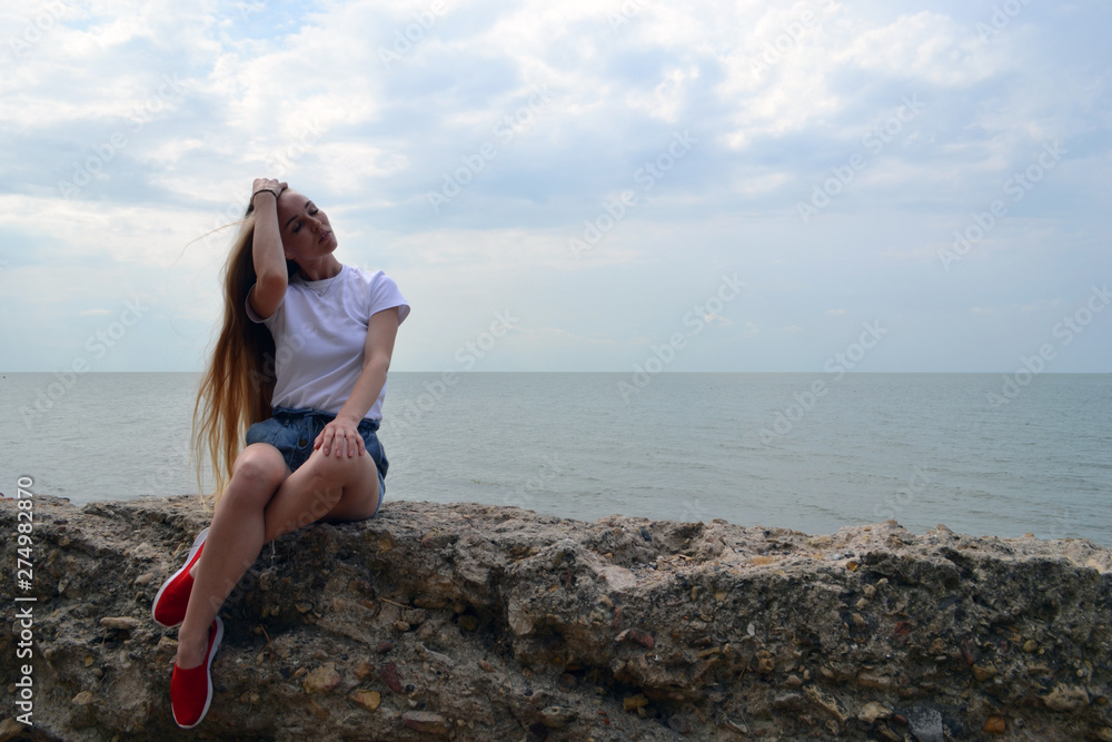 Young woman in white t-shirt relaxing by the sea