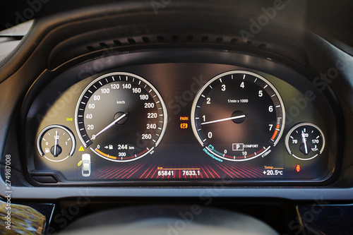 Electronic dashboard of modern luxury car with electronic display and with white arrows speedometer tachometer and other tools