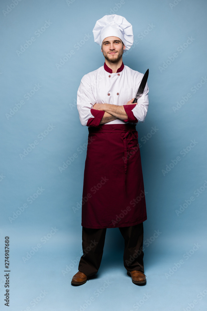 Handsome male chef cook holding knifes isolated on light blue background. Handsome male chef cook holding knifes isolated on light blue background.
