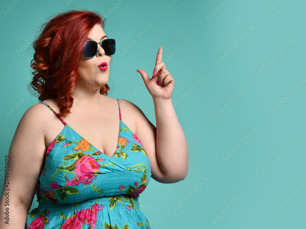 Plus-size overweight lady in sunglasses and sundress point her finger up  like she has got an idea at free text copy space on mint Stock Photo |  Adobe Stock
