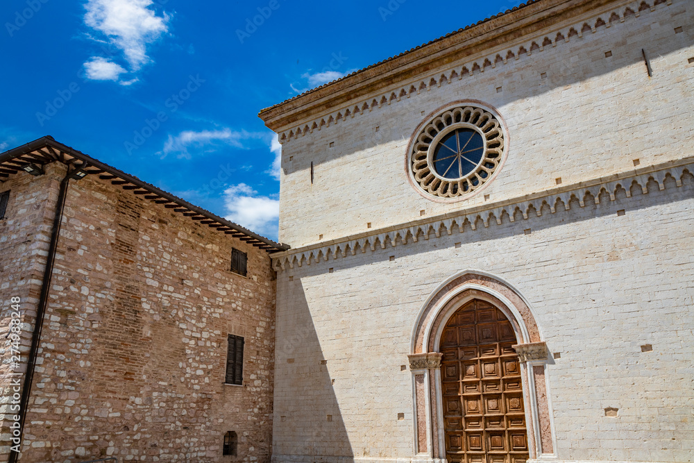 The monastery of the Poor Clares. The wooden portal with a pointed arch and the rose window. In Spello, province of Perugia, Umbria, Italy.