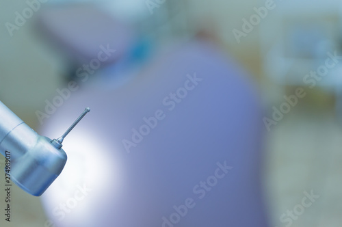 Dental handpiece with diamond bur close-up against the background of the dental chair. photo