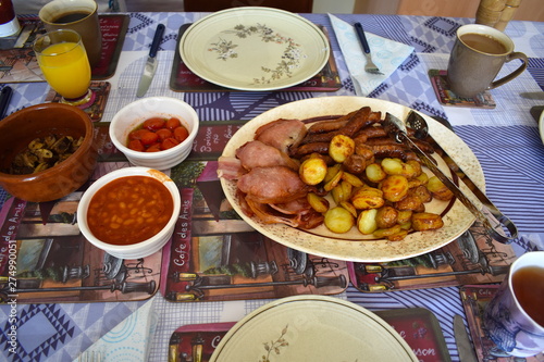 The components of traditional English breakfast include sausage, bacon, beans, tomato, toast, eggs, mushrooms, potatoes, black pudding, coffee or tea. Rothwell, Northamptonshire, UK photo