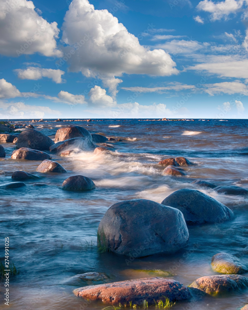 Fototapeta premium Long Exposure waves at the Ladoga lake. Beautiful scape with stone beach, reeds and water. Ladoga lake, Karelia, Russia.