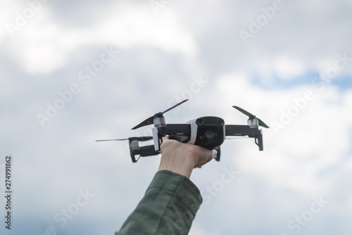 Flying drone in a female hand against the sky.