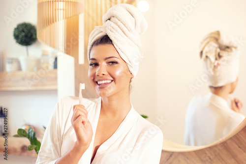 Woman brushing her teeth in bathroom.