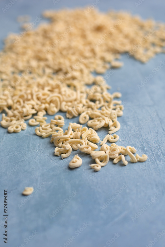 Homemade Small Macaroni Pasta Scattered on Blue Background Homemade Small Macaroni Pasta Scattered on Blue Background