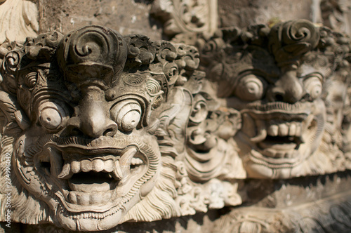 Beautiful Balinese masks engraved in a stone wall