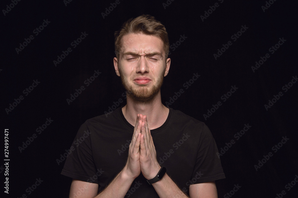 Close up portrait of young man isolated on black studio background. Photoshot of real emotions of male model. Praying with closed eyes, looks hopeful. Facial expression, human emotions concept. Close up portrait of young man isolated on black studio background. Photoshot of real emotions of male model. Praying with closed eyes, looks hopeful. Facial expression, human emotions concept.