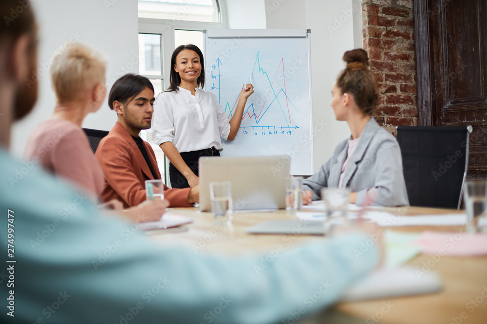 Portrait of mixed race businesswoman standing by whiteboard and giving presentation to colleagues during meeting in conference room, copy space Portrait of mixed race businesswoman standing by whiteboard and giving presentation to colleagues during meeting in conference room, copy space