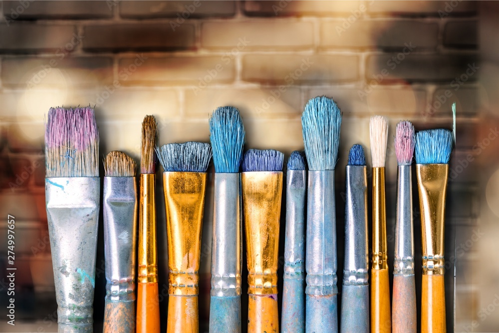 Artist brushes and paint on wall background - obrazy, fototapety, plakaty 