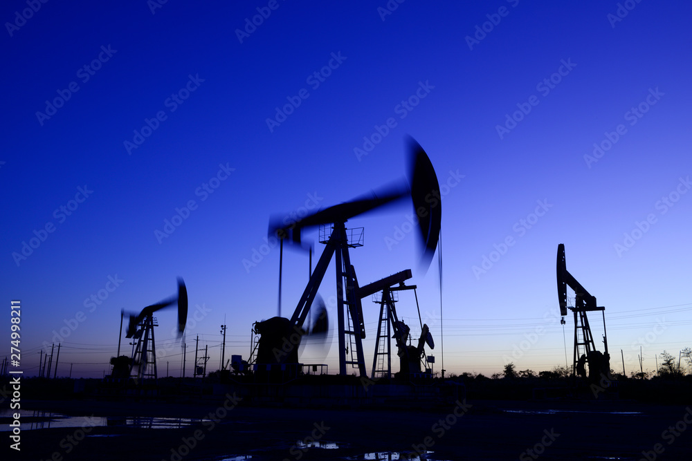 The pumping unit is working, silhouetted against the setting sun