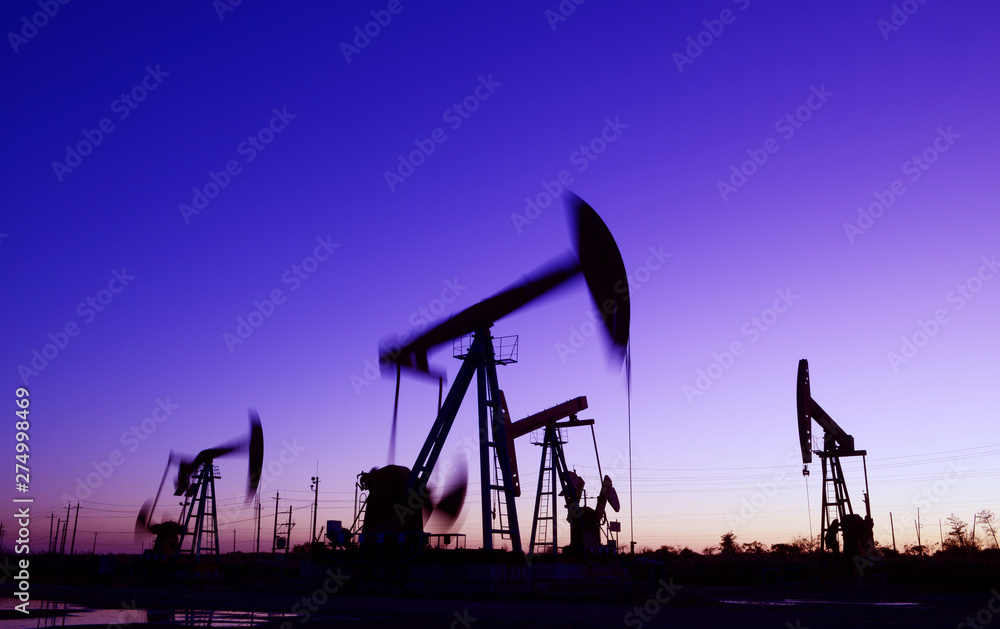 The pumping unit is working, silhouetted against the setting sun The pumping unit is working, silhouetted against the setting sun