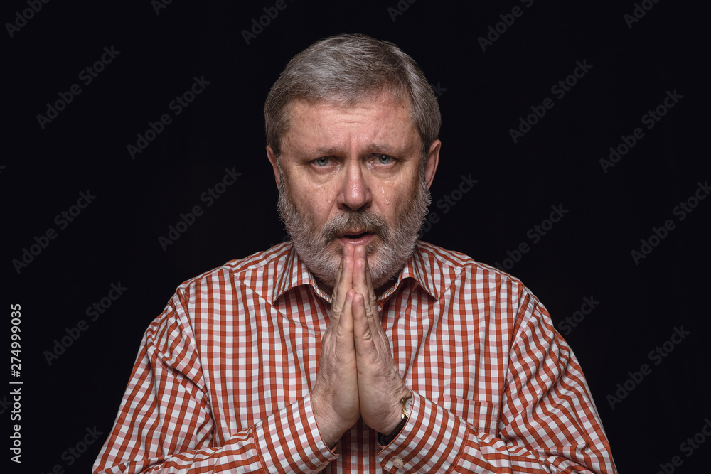Close up portrait of senior man isolated on black studio background. Photoshot of real emotions of male model. Praying and crying, sad and hopeful. Facial expression, human emotions concept. Close up portrait of senior man isolated on black studio background. Photoshot of real emotions of male model. Praying and crying, sad and hopeful. Facial expression, human emotions concept.