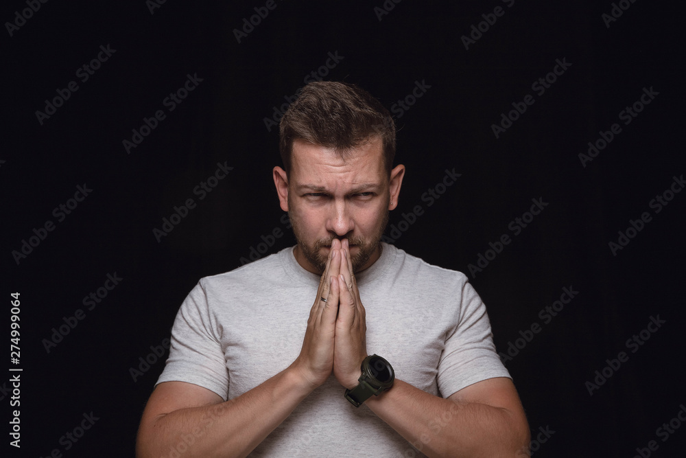 Close up portrait of young man isolated on black studio background. Photoshot of real emotions of male model. Praying with closed eyes, looks hopeful. Facial expression, human emotions concept. Close up portrait of young man isolated on black studio background. Photoshot of real emotions of male model. Praying with closed eyes, looks hopeful. Facial expression, human emotions concept.