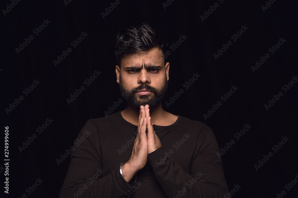 Close up portrait of young man isolated on black studio background. Photoshot of real emotions of male model. Praying looking forward, sad and hopeful. Facial expression, human emotions concept. Close up portrait of young man isolated on black studio background. Photoshot of real emotions of male model. Praying looking forward, sad and hopeful. Facial expression, human emotions concept.