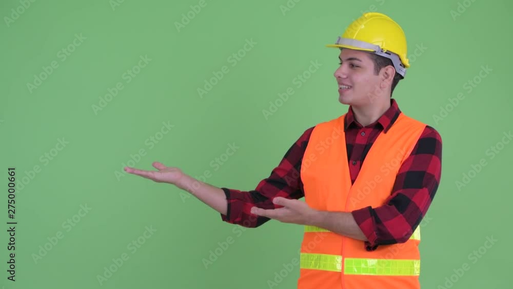 Happy young multi ethnic man construction worker talking while showing something Happy young multi ethnic man construction worker talking while showing something