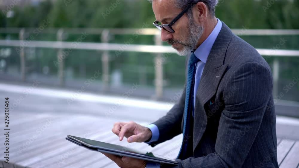 Middle aged male entrepreneur checking email with media files from business partner searching financial  report and documentation connected to 4g wireless interneton modern touch pad