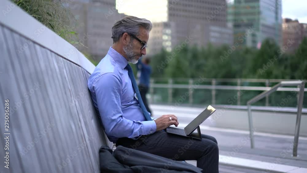 Mature businessman checking notification on smartphone gadget while working at online platform with financial documents using 4g wireless on modern touch pad during work break on urban setting Mature businessman checking notification on smartphone gadget while working at online platform with financial documents using 4g wireless on modern touch pad during work break on urban setting