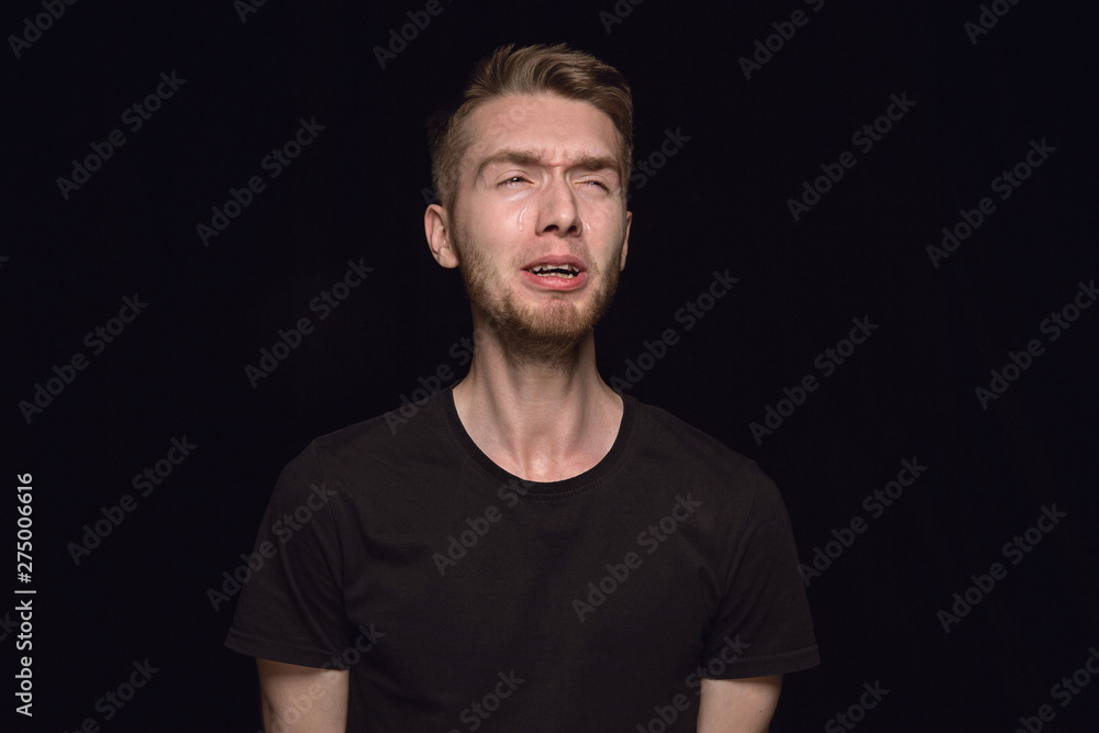 Close up portrait of young man isolated on black studio background. Photoshot of real emotions of male model. Crying, sad, dreary and hopeless. Facial expression, human emotions concept. Close up portrait of young man isolated on black studio background. Photoshot of real emotions of male model. Crying, sad, dreary and hopeless. Facial expression, human emotions concept.