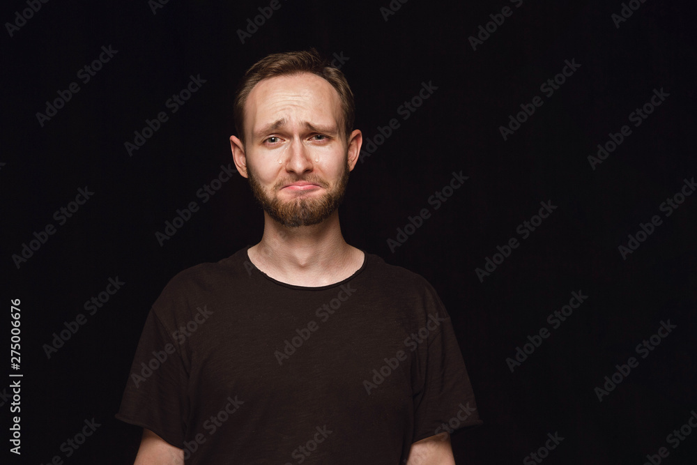 Close up portrait of young man isolated on black studio background. Photoshot of real emotions of male model. Crying, sad, dreary and hopeless. Facial expression, human emotions concept. Close up portrait of young man isolated on black studio background. Photoshot of real emotions of male model. Crying, sad, dreary and hopeless. Facial expression, human emotions concept.