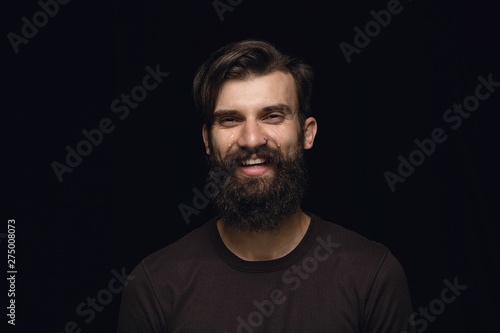 Close up portrait of young man isolated on black studio background. Photoshot of real emotions of male model. Crying throught laughting and smiling. Facial expression, human emotions concept.