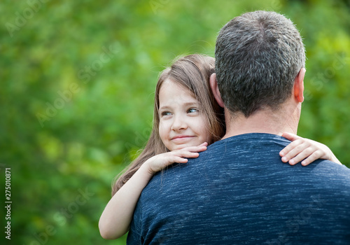 Portrait of cute little girl held in father's arms. Happy loving family. Father and his daughter child girl playing hugging. Cute baby and daddy. Concept of Father day. Family holiday and togetherness